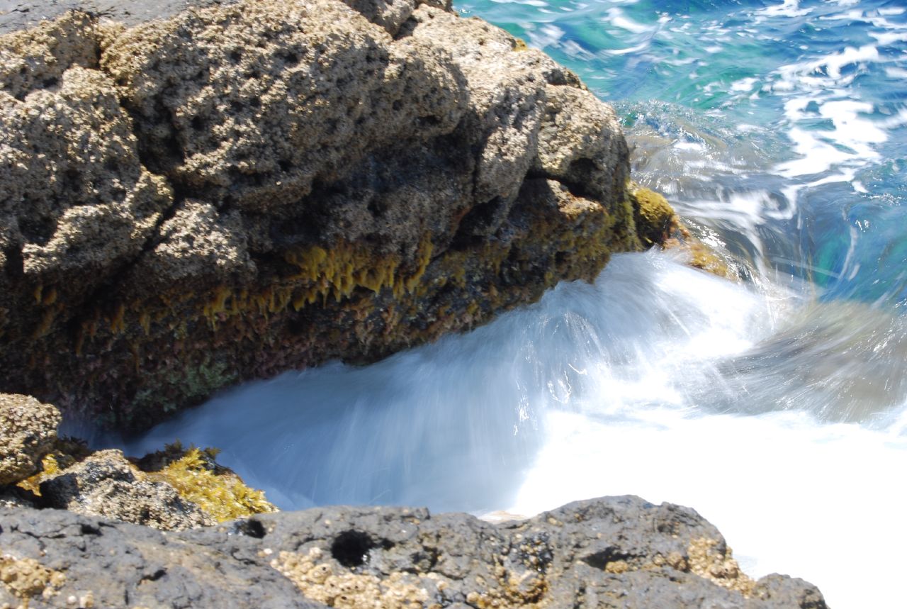 Waves spilling into the Laghetto delle Ondine natural rock pool on Pantelleria's lava coast